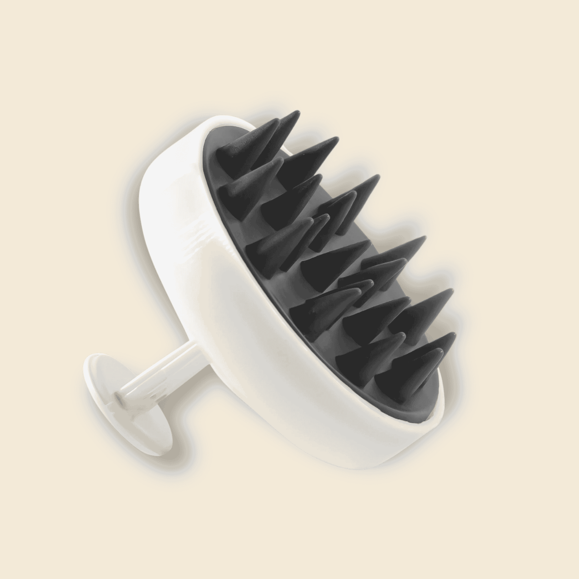 A white and black silicone scalp massage brush with a circular head and a single stem, shown on a solid light beige background.